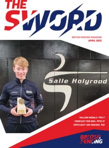 Front cover of foil fencer Jaimie Cook holding a trophy on the April 2023 edition of The Sword magazine