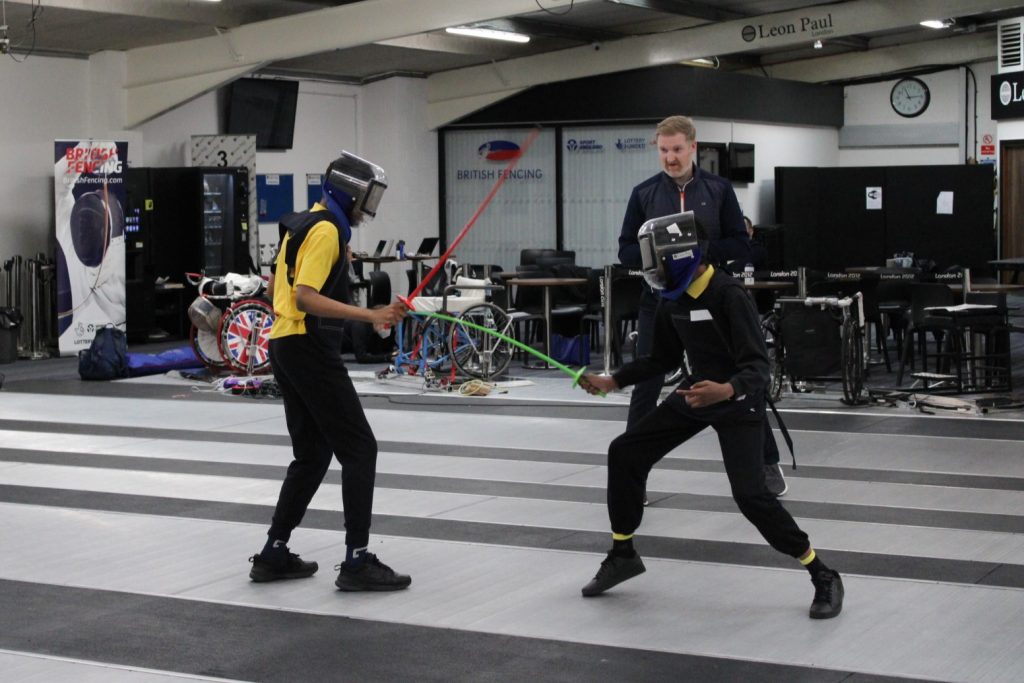 Two young fencers using plastic kit in a bout