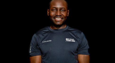 A coach in a British Fencing Kukri t-shirt smiles to the camera.
