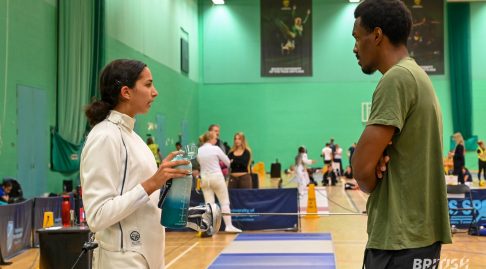 A coach and an epee fencer are talking at a competition.