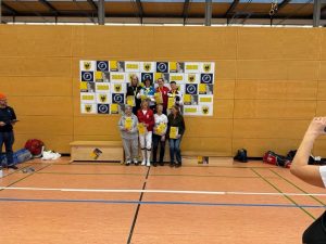 Several fencers on a podium holding certificates.
