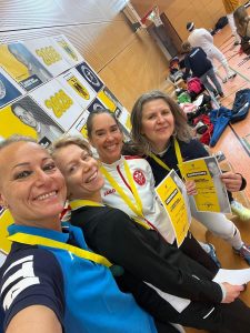 Four fencers on a podium take a selfie.
