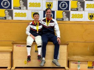 Two fencers sitting next to each other wearing medals.