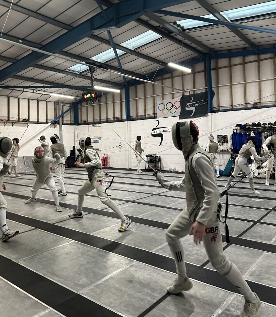 Several foil fencers fencing in a salle.