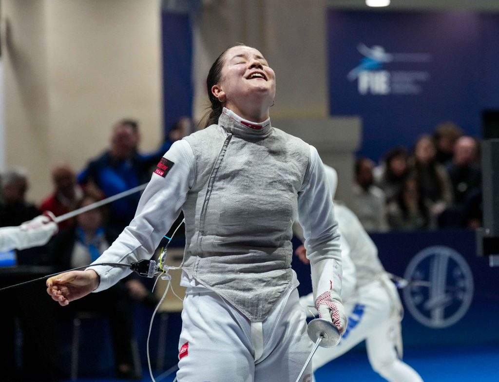 A GBR foil fencer looks up in relief after winning a match.