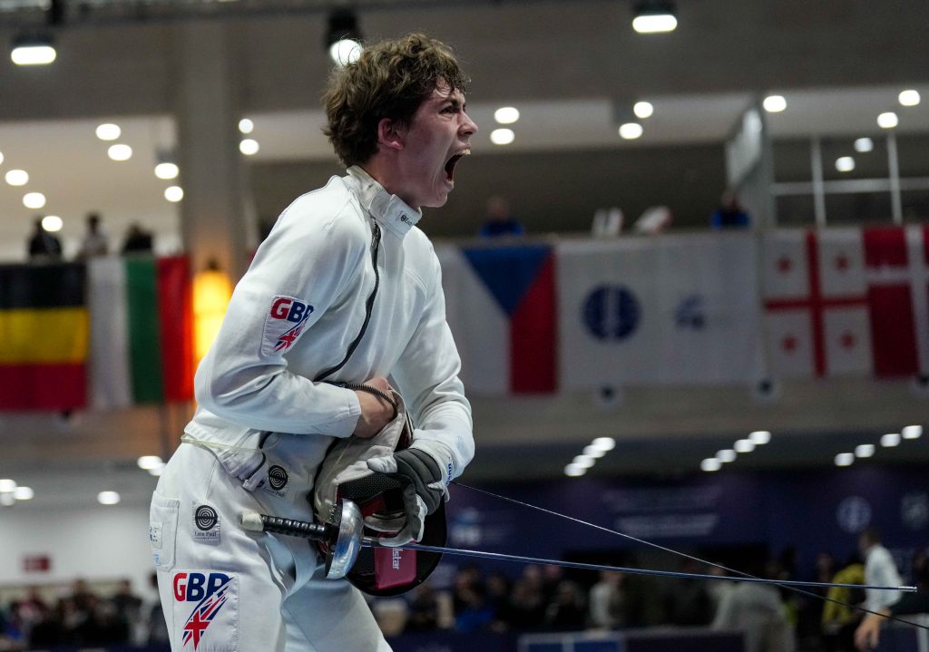 A GBR epee fencer yells in celebration after winning a match.