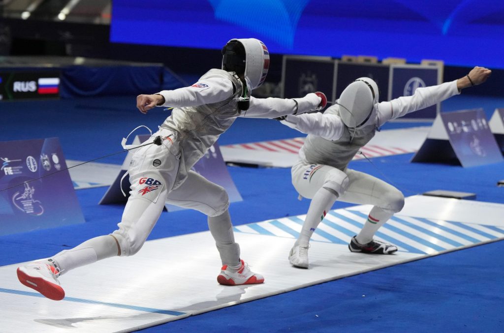 Two foil fencers in action, one representing GBR and the other Hungary