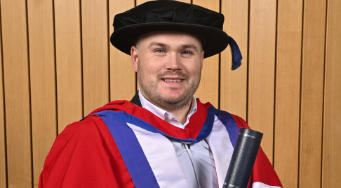 Rick Rodgers in graduation wear smiles to the camera.