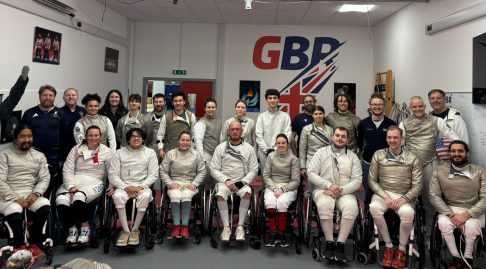 A large group of GBR para fencers and coaches smile to the camera.