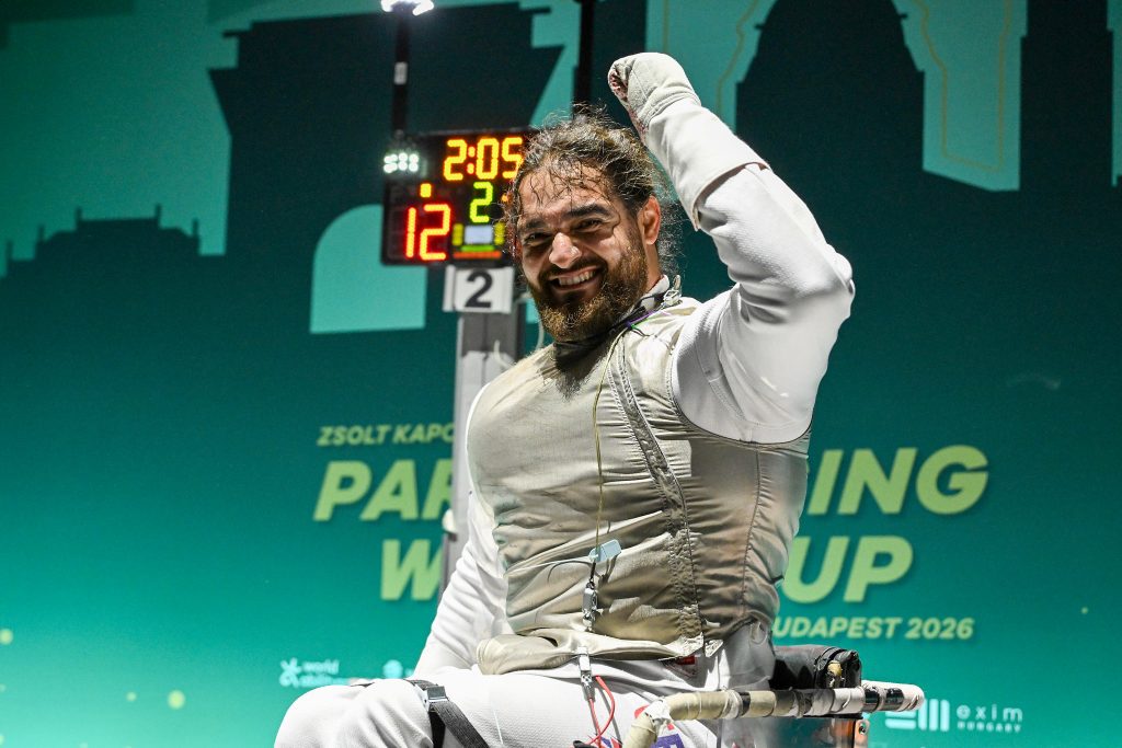 A GBR foil para fencer cheers and raises their fist after a win