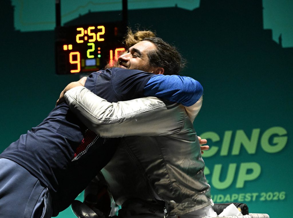 A GBR sabre para fencer hugs his coach.