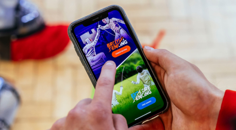 A person's hand using a British Fencing Explore Fencing app on their phone.
