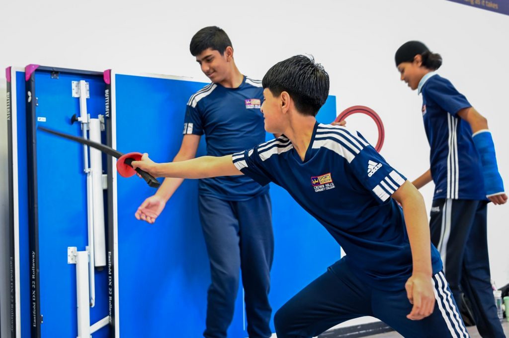 Students at Crown Hills take part in fencing activities using foam swords and hoops.