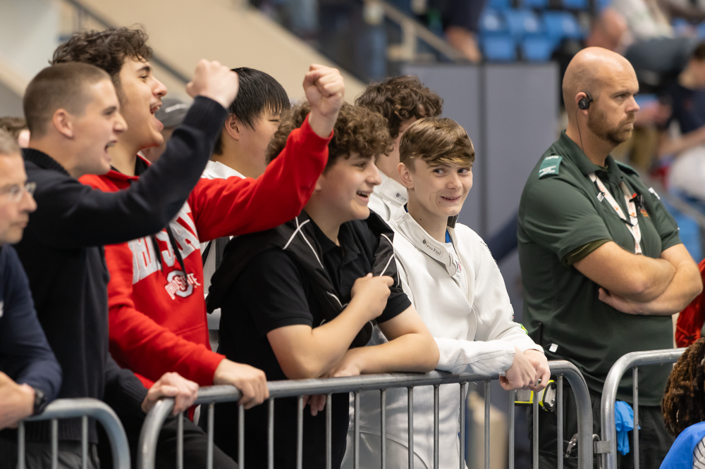 A group of young spectators are cheering for someone out of view.