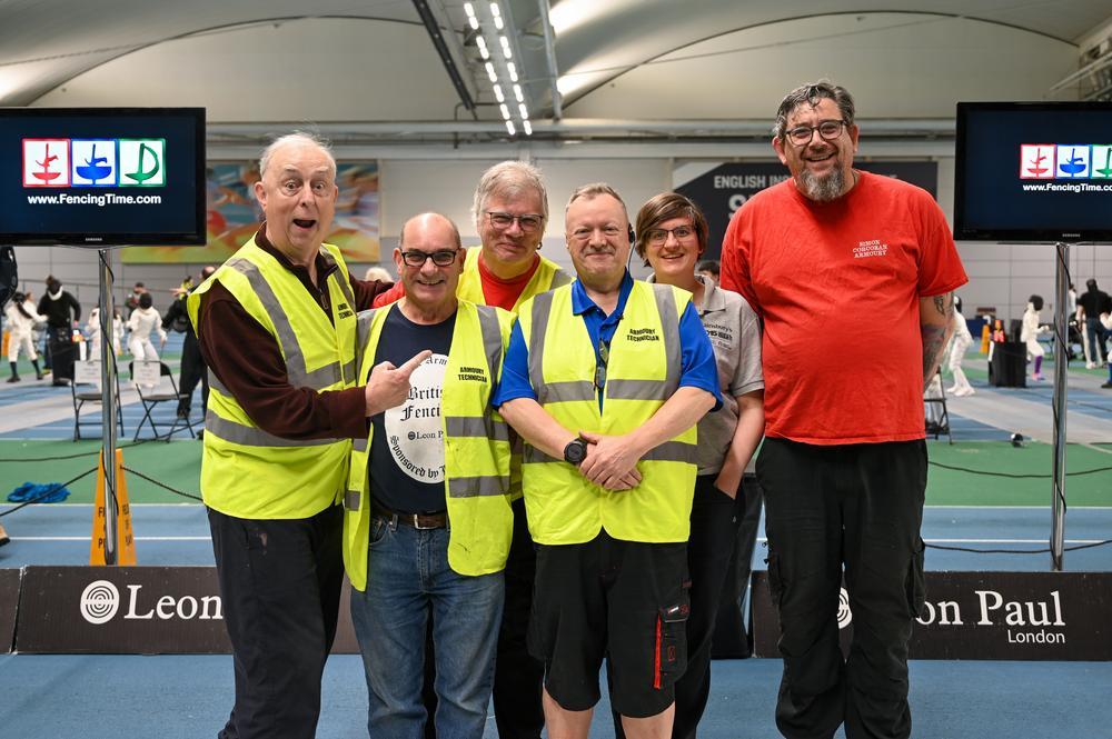 A group of armourers, some in high vis jackets, smile to the camera.