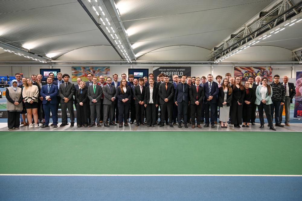 A large group of referees standing on a piste smile to the camera.