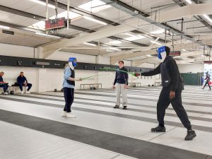 Callum Penman referees two people fencing with plastic kit