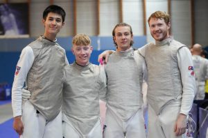Four GBR foil fencers smile to the camera