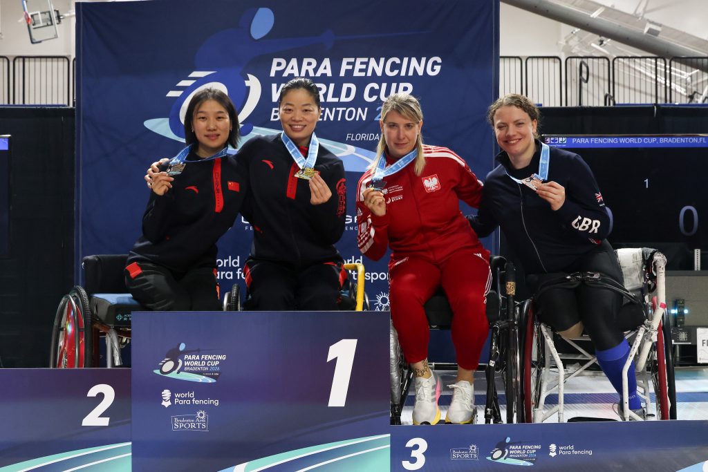 Four para fencers are on a podium smiling to the camera, each wearing a medal. L-R: CHN, CHN, POL, GBR.