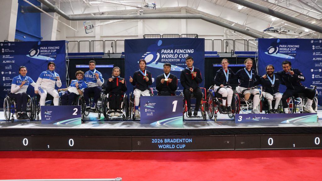 Three para fencing teams are on a podium smiling to the camera, each wearing medals. L-R: ITA, CHN, GBR.