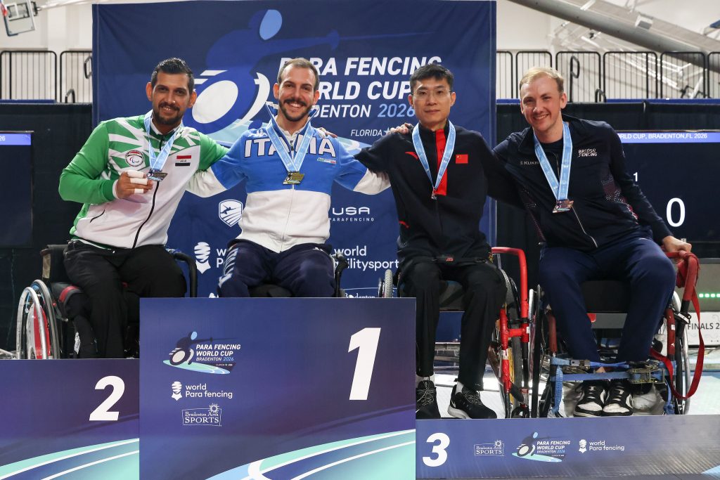 Four para fencers are on a podium smiling to the camera, each wearing a medal. L-R: IRQ, ITA, CHN, GBR.