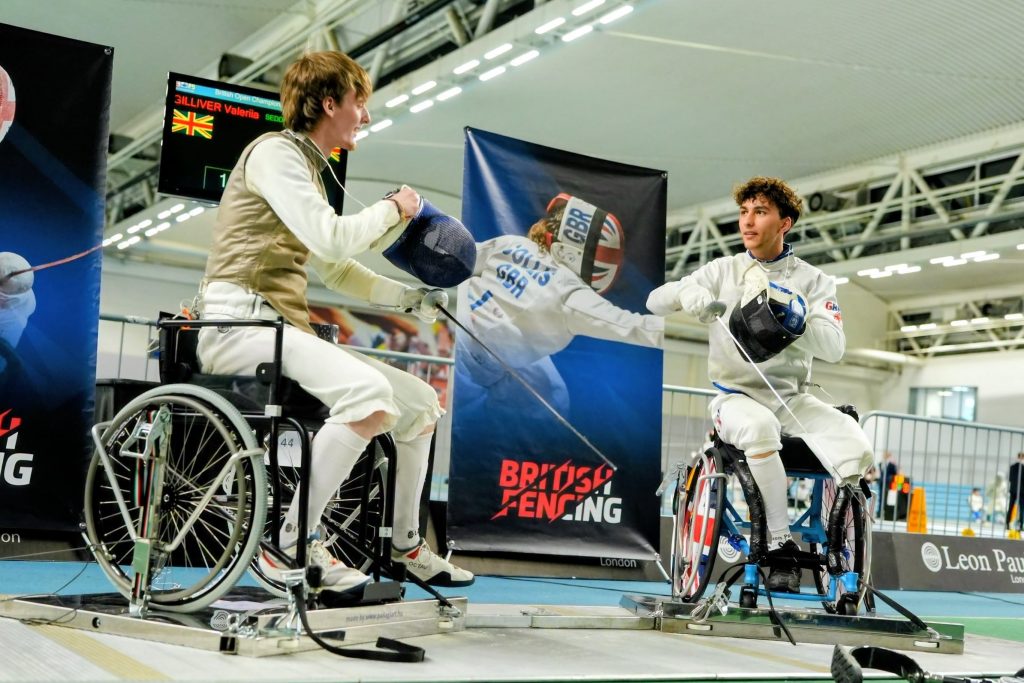 Two foil wheelchair fencers at a competition go to test their weapons