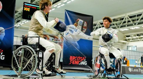 Two foil wheelchair fencers at a competition go to test their weapons