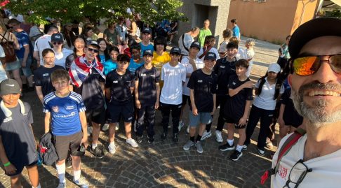 A large group of young fencers and Marco Zaffino smile for a selfie outside
